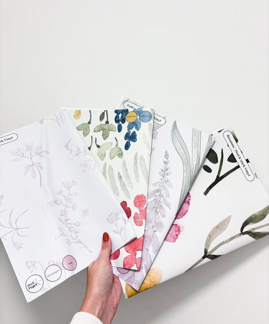 An Image of A Womans Hand Which is Holding Samples Of Peel & Paper's Floral Designs