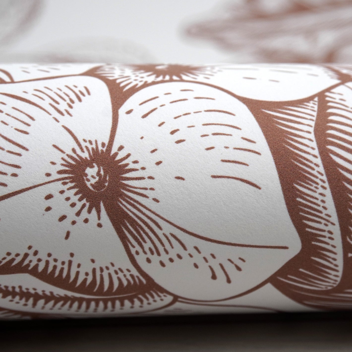 Close up image of the surface of Peel & Paper peel & stick wallpaper printed with a brown floral design.