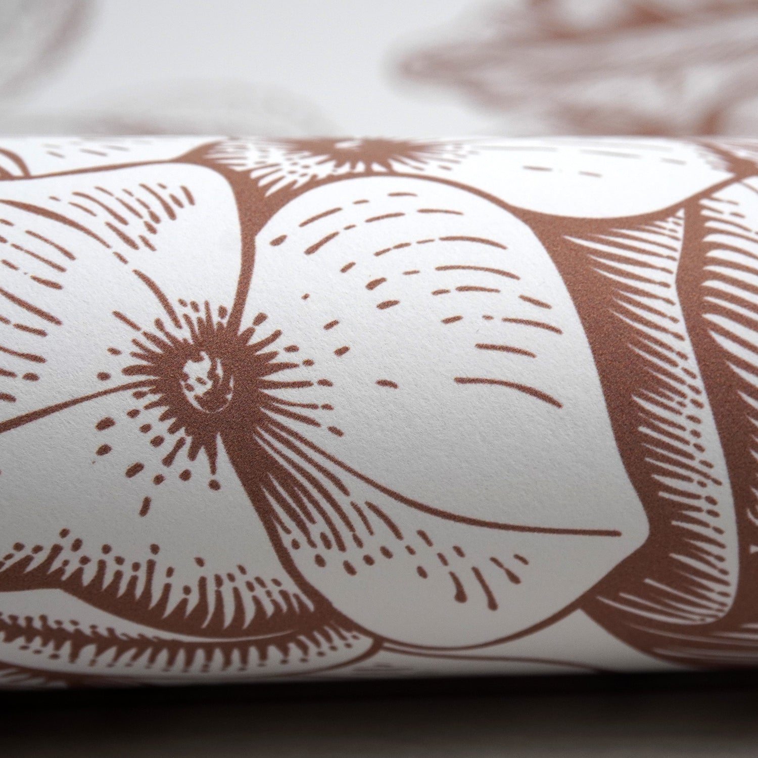 Close up image of the surface of Peel & Paper peel & stick wallpaper printed with a brown floral design.