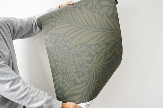 a person holding up a green wallpaper roll