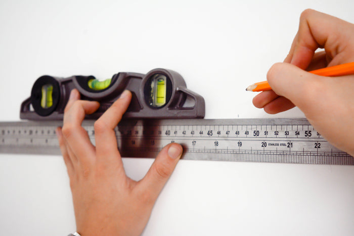 Ruler and spirit level measuring up for wallpaper installation