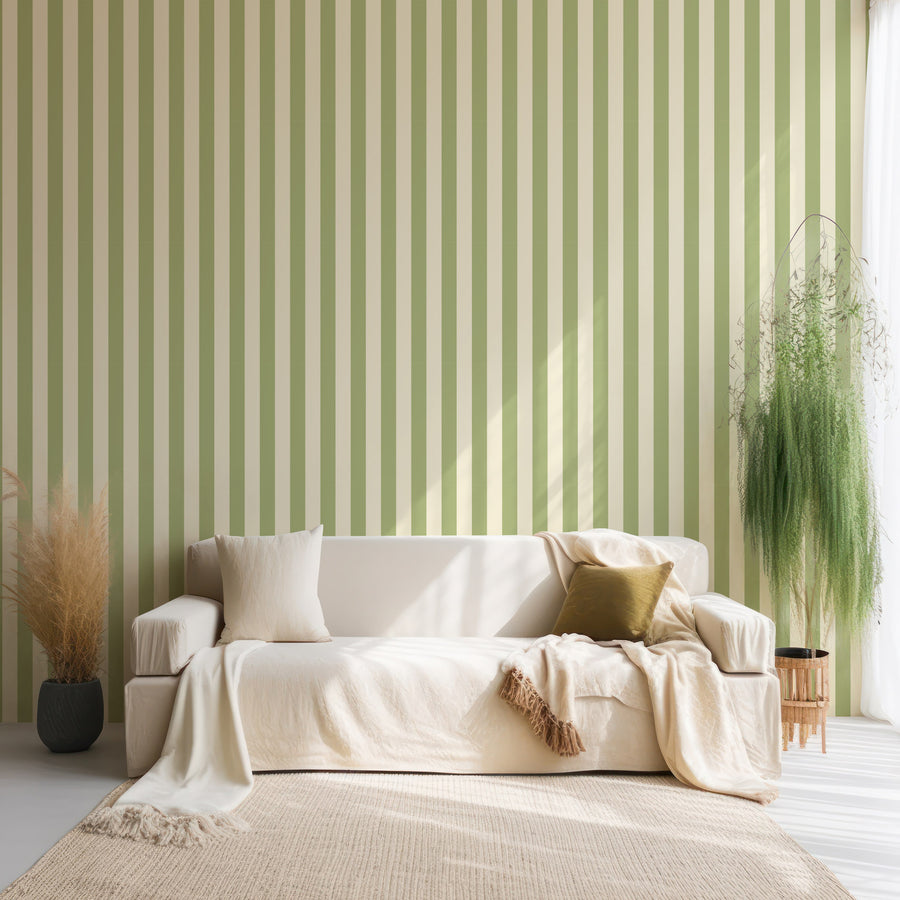 A living room with a cream fabric living room with plants either side of it featuring the Boudica wallpaper which is a modern striped wallpaper with alternating vertical bands in two custom colours creating a simple geometric design.