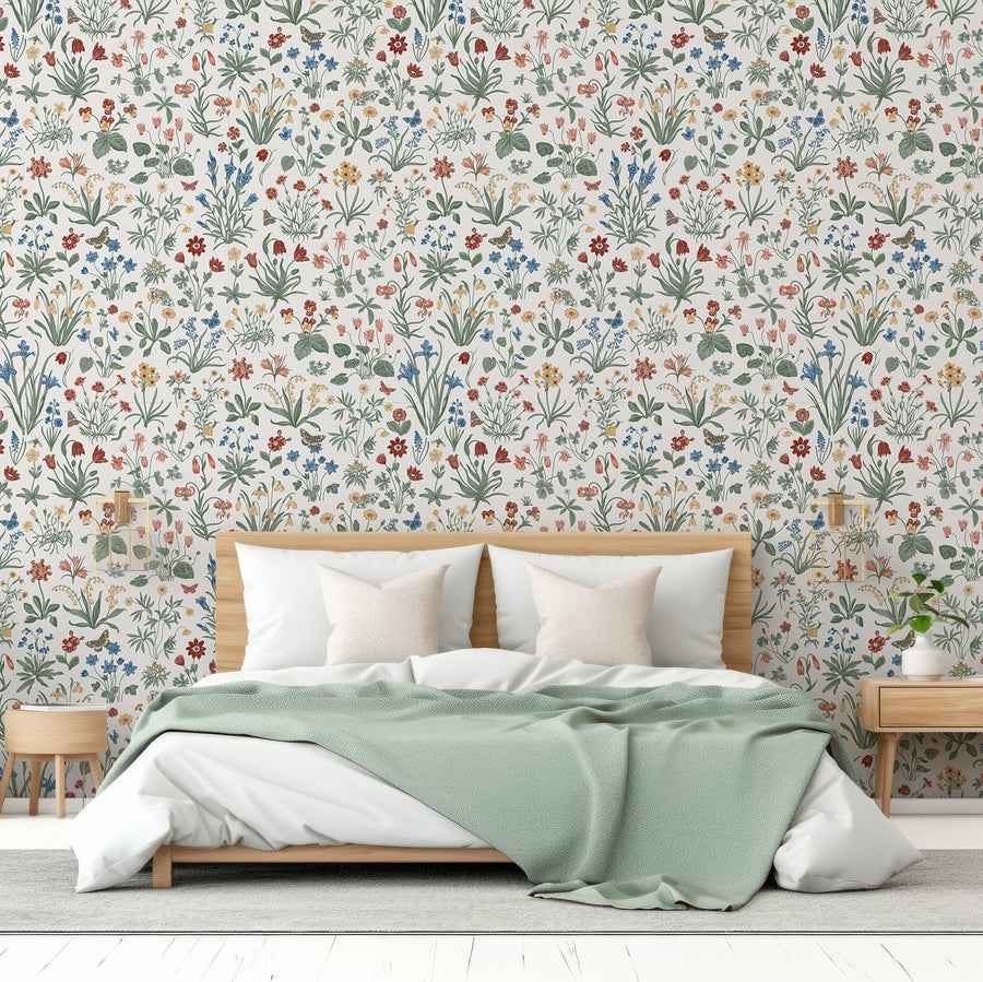 A bedroom with light coloured furniture featuring the Mallory wallpaper which is pastel botanical with colourful flowers, leafy plants and butterflies on a light grey background in a delicate repeating pattern.