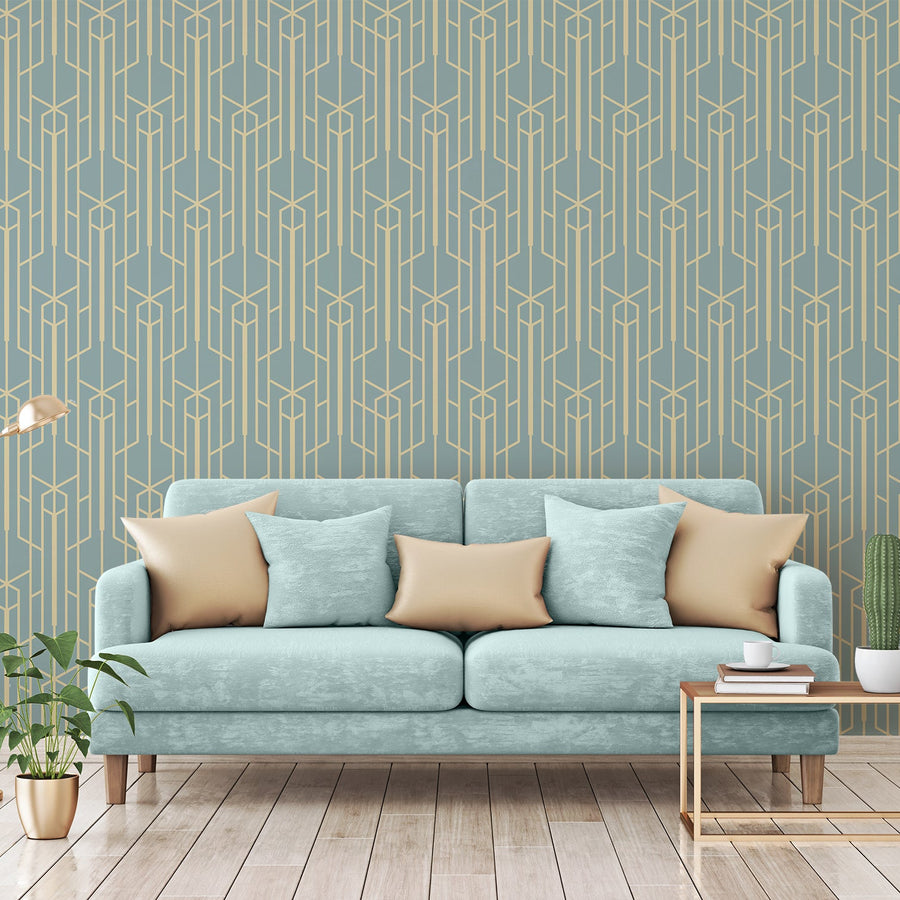 A living room showing a light blue sofa scattered with pillows featuring 'Seraphina' which is a teal wallpaper featuring elegant gold geometric lines in a vintage Art Deco pattern with repeating fan and diamond motifs.