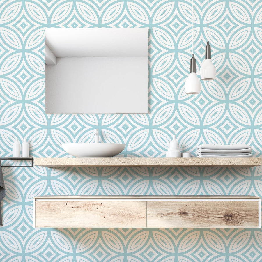 A bathroom with a sink and mirror featuring 'Amphitrite' which is a blue Art Deco wallpaper featuring bold geometric fan shapes and angular line details in a repeating vintage-inspired pattern.
