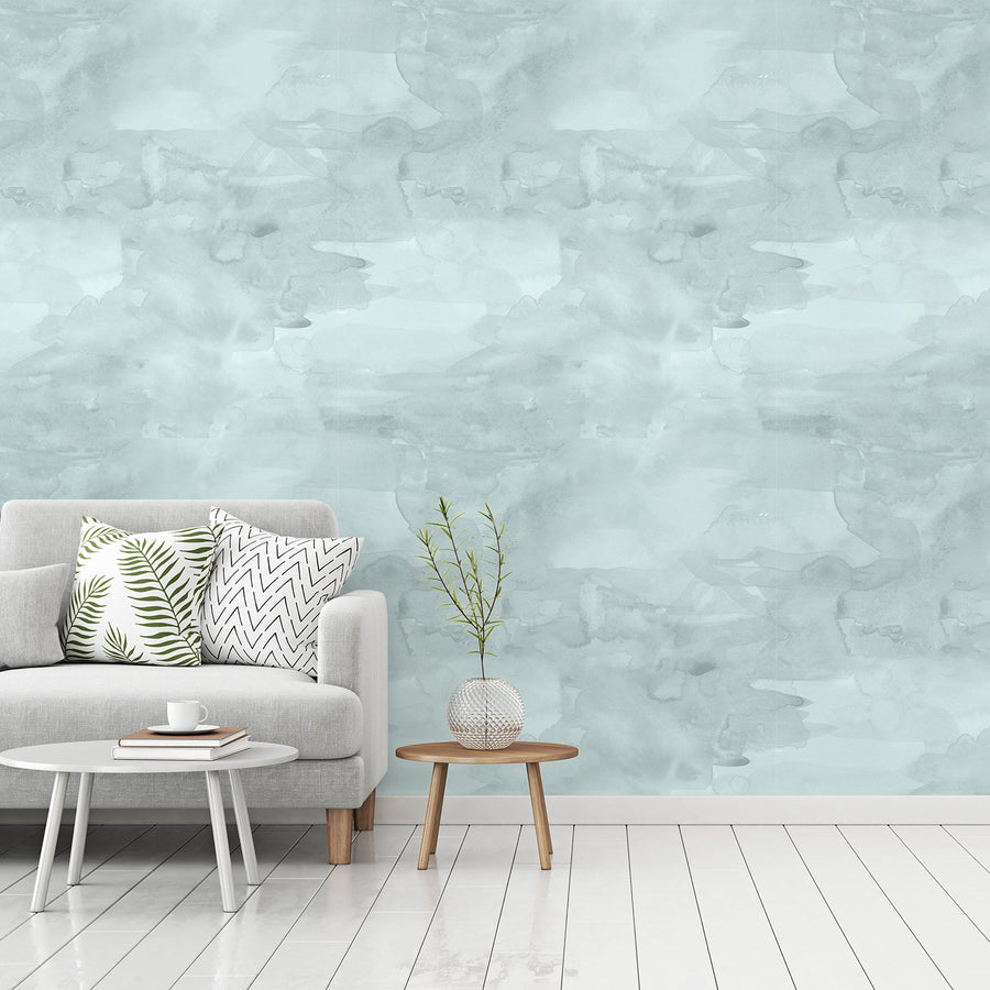 A living room with a grey sofa featuring the Lucinda wallpaper which is watercolour soft brush stroke textures with a flowing painted effect in a customisable colour palette.